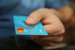 e-commerce website A close-up shot of a hand offering a blue debit card for payment.